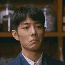 a man in a blue jacket and white shirt is making a sad face