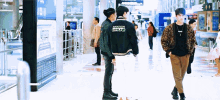 a man wearing a jacket that says maison kitsune is standing next to another man .