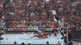 a wrestler is jumping over another wrestler in front of a crowd that is watching a match sponsored by old wives