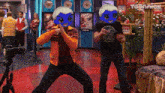 two men wearing anime masks are dancing in a room with a sign that says toonnick