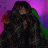 a woman in a plaid shirt covers her face with her hands