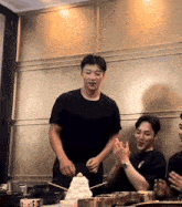 a man in a black t-shirt is standing in front of a stack of ice cream