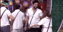 a group of people are standing around a man in a white shirt and a woman in a white dress .