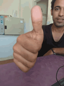 a man is giving a thumbs up in front of a machine that says ' ec ' on it