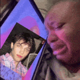 a woman is crying while looking at a picture of a boy