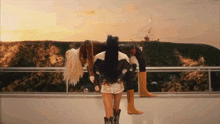 a woman wearing cowboy boots is standing on a balcony with a mountain in the background