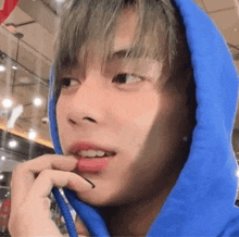 a close up of a person wearing a blue hoodie with a pencil in their mouth .