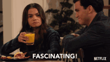 a man and a woman are sitting at a table and the woman is holding a glass of orange juice