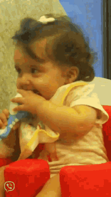 a baby is sitting in a red chair with a whatsapp icon on it