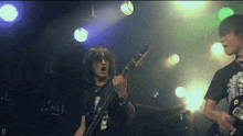 a man playing a guitar on a stage with the letter d in the corner