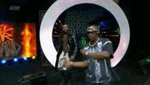 two men are dancing on a stage with a aew logo in the background