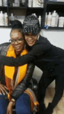 two women hugging each other in a room with bottles of shampoo on the shelves