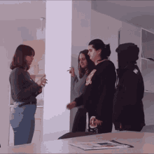 a woman wearing a black sweatshirt with the number 3 on it talks to two other women