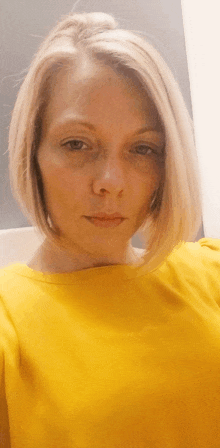 a woman wearing a yellow shirt looks at the camera