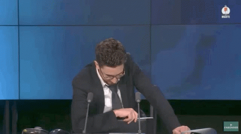 a man in a suit and tie is sitting in front of microphones and says font plaisir a voir