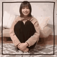 a woman is sitting on the floor in front of a couch wearing striped slippers .