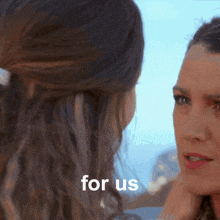 two women are looking at each other and the words for us are behind them
