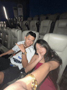 a man in a tnrm shirt sits next to a woman in a movie theater