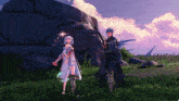 a man and a woman standing next to each other in front of a large rock