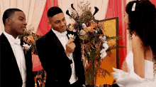 a bride and groom are standing next to each other in front of a bouquet of flowers at a wedding reception .