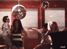 a group of people dancing in front of a disco ball