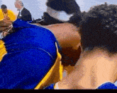 a man in a blue and yellow shirt is kissing another man on the cheek .
