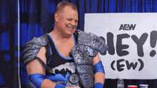 a wrestler stands in front of a sign that says aew