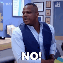 a man in a blue vest and white shirt is making a no sign .