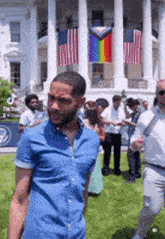 a man in a blue shirt is standing in front of the white house