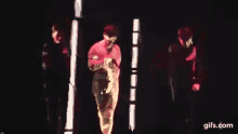 a group of people are dancing on a stage in red lights .