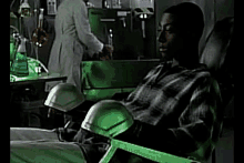 a man in a plaid shirt is sitting in a green chair in a lab .