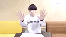 a boy is sitting at a table with his hands outstretched .