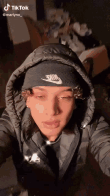 a young man wearing a hooded jacket and a black beanie is taking a selfie .
