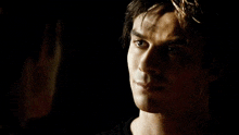 a man with a serious look on his face stands next to another man in a dark room