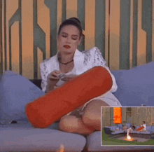 a woman is sitting on a couch holding a red pillow