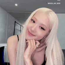 a woman with long blonde hair and a ring on her finger smiles