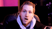 a man is sitting in a chair with his mouth open and making a surprised face .