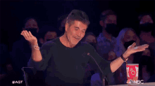 a man in a black shirt is clapping in front of a crowd while holding a cup that says coca cola