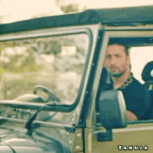 a man is sitting in a tan jeep with tanuja written on the side