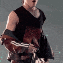 a man wearing a black tank top and a red and black jacket