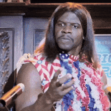 a man with long hair is standing in front of a microphone wearing a hawaiian lei