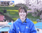 a woman wearing a blue adidas jacket smiles
