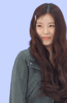 a woman with long brown hair is wearing a green leather jacket