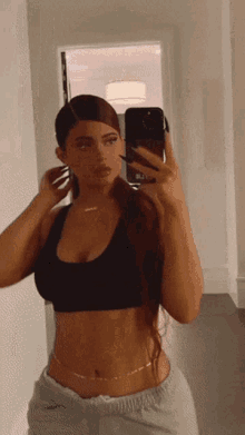 a woman taking a picture of herself in a mirror with her phone