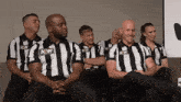 a group of men wearing aew striped shirts sit in a row