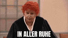 a woman with red hair and glasses is standing in a courtroom and says in aller ruhe .