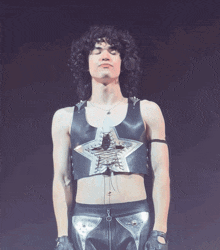 a man with curly hair is wearing a black leather vest with a silver star on it