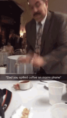 a man in a suit and tie spills coffee on a table