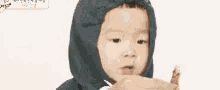 a baby wearing a blue hoodie is making a funny face .