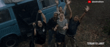 a group of people standing in front of a blue van